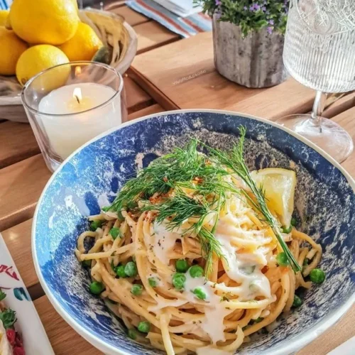 Pasta med sitron og friske erter servert på en tallerken.