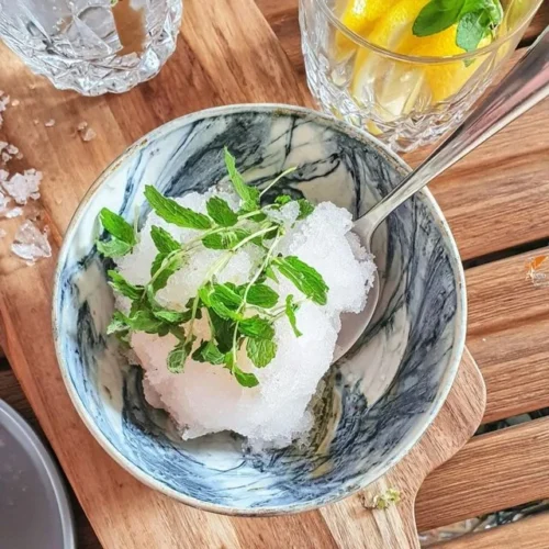 Sitrungranita med frisk mynte servert i en glassbeholder.